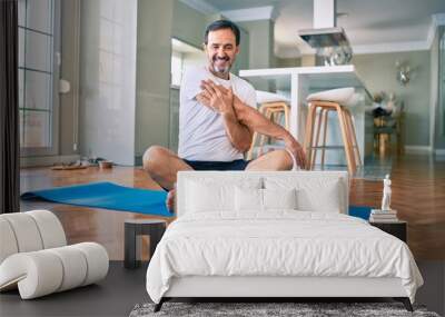 Middle age man with beard training and stretching doing exercise at home looking at sport video on computer Wall mural