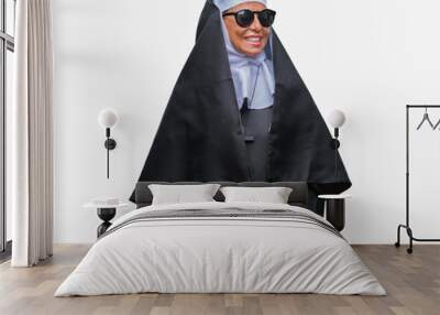 Middle age senior catholic nun woman wearing sunglasses over isolated background looking away to side with smile on face, natural expression. Laughing confident. Wall mural