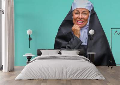 Middle age senior christian catholic nun woman over isolated background looking stressed and nervous with hands on mouth biting nails. Anxiety problem. Wall mural