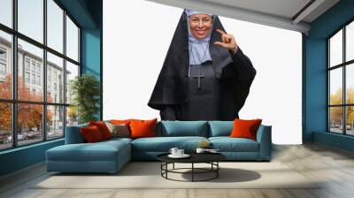 Middle age senior christian catholic nun woman over isolated background smiling and confident gesturing with hand doing size sign with fingers while looking and the camera. Measure concept. Wall mural