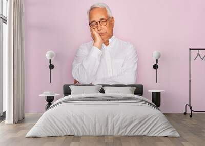 Middle age senior grey-haired man wearing glasses and business shirt over pink background thinking looking tired and bored with depression problems with crossed arms. Wall mural