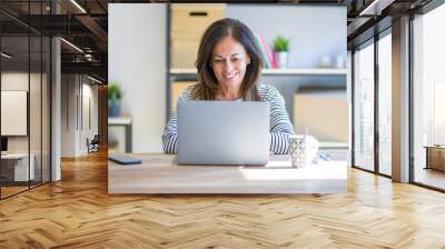 Middle age senior woman sitting at the table at home working using computer laptop with a happy and cool smile on face. Lucky person. Wall mural