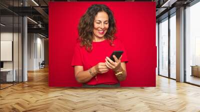 Middle age senior woman using smartphone over red isolated background with a happy face standing and smiling with a confident smile showing teeth Wall mural