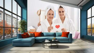 Middle age woman and daughter wearing bath robe holding heart card smiling with a happy and cool smile on face. showing teeth. Wall mural