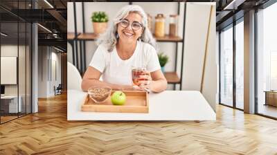 Middle age woman smiling confident having breakfast at home Wall mural