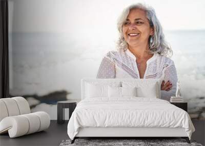 Middle age woman smiling confident standing with arms crossed gesture at seaside Wall mural