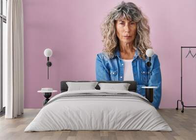 Middle age woman standing over pink background skeptic and nervous, disapproving expression on face with crossed arms. negative person. Wall mural