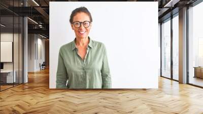 Middle age woman wearing green shirt and glasses standing over isolated white background with a happy and cool smile on face. Lucky person. Wall mural