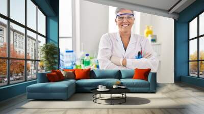 Middle age woman wearing scientist uniform standing with arms crossed gesture at laboratory Wall mural