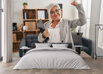 Middle age woman with grey hair at consultation office strong person showing arm muscle, confident and proud of power Wall mural