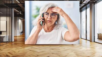 Middle age woman worried talking on the smartphone at home Wall mural