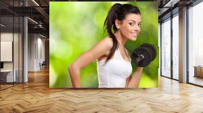 portrait of a young pretty woman holding weights and doing fitne Wall mural