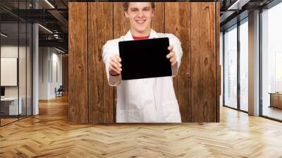 portrait of young man showing digital tablet against a wooden wa Wall mural