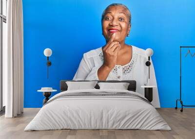 Senior african american woman wearing casual clothes smiling looking confident at the camera with crossed arms and hand on chin. thinking positive. Wall mural