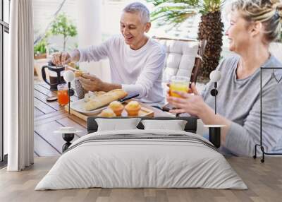 Senior caucasian couple smiling happy having breakfast at the terrace. Wall mural