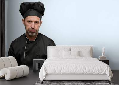 Senior cook man, wearing chef hat with sleepy expression, being overworked and tired isolated over blue background Wall mural