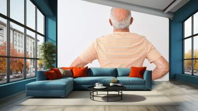 Senior grey-haired man wearing striped t-shirt standing over isolated white background standing backwards looking away with arms on body Wall mural