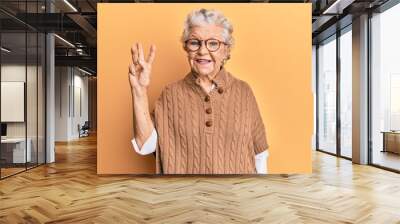 Senior grey-haired woman wearing casual clothes and glasses showing and pointing up with fingers number three while smiling confident and happy. Wall mural