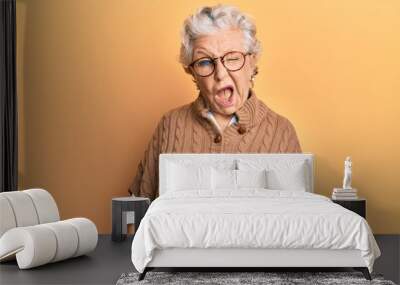 Senior grey-haired woman wearing casual clothes and glasses winking looking at the camera with sexy expression, cheerful and happy face. Wall mural