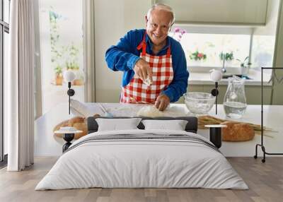 Senior man smiling confident pouring flour on dough at kitchen Wall mural