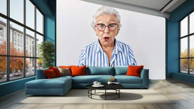 Senior woman with grey hair standing over white background afraid and shocked with surprise expression, fear and excited face. Wall mural