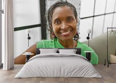 Smiling african american mature woman in casual green attire indoors Wall mural