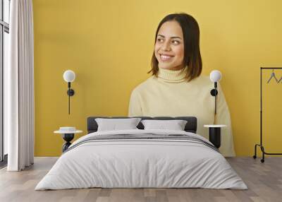 Smiling young hispanic woman in casual attire against a vibrant yellow background, exuding warmth and positivity. Wall mural