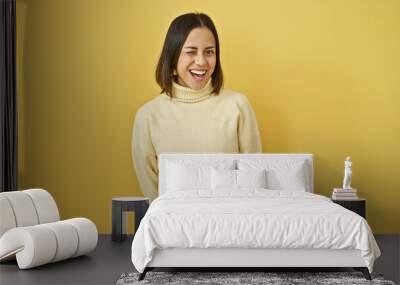 Smiling young hispanic woman posing against a vibrant yellow background, exuding cheerful beauty. Wall mural