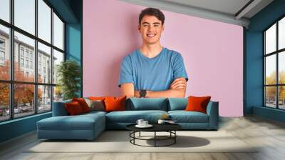 Teenager boy wearing casual t-shirt standing over blue isolated background happy face smiling with crossed arms looking at the camera. Positive person. Wall mural