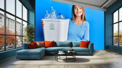 Teenager caucasian girl holding recycling bag with plastic bottles celebrating crazy and amazed for success with open eyes screaming excited. Wall mural