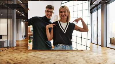 Two beautiful business workers wearing business style standing at the office looking confident with smile on face, pointing oneself with fingers proud and happy. Wall mural