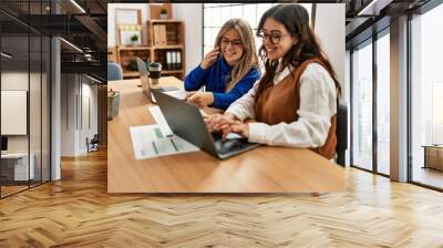 Two business workers woman talking on the smartphone and using laptop at the office. Wall mural