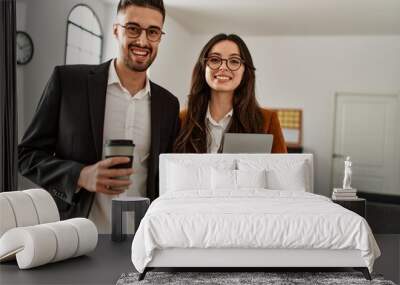 Two hispanic business workers smiling happy drinking coffee at the office. Wall mural