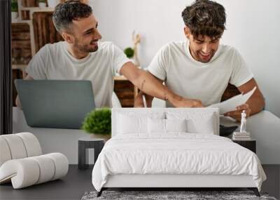 Two hispanic men couple smiling confident using laptop working at home Wall mural