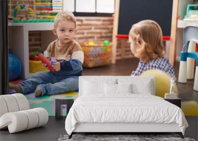 Two kids playing with construction blocks sitting on floor at kindergarten Wall mural