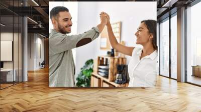 Two latin business workers smiling happy high five with hands raised up at the office. Wall mural