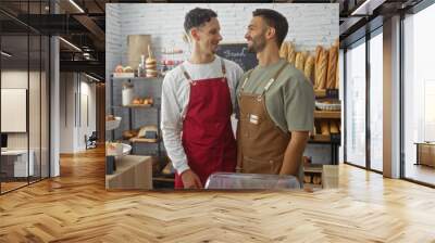 Two men, bakers working together in a cozy bakery, smiling at each other surrounded by bread and pastries in an indoor shop setting Wall mural