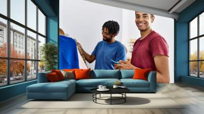 Two men friends choosing clothes using smartphone at clothing store Wall mural