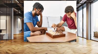 Two men friends playing chess sitting on sofa at home Wall mural