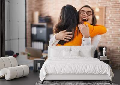 Two women business workers hugging each other at office Wall mural