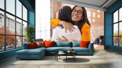 Two women business workers hugging each other at office Wall mural