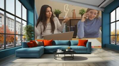 Two women converse in a modern living room, one gesturing while the other chats on a smartphone Wall mural