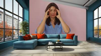 Woman suffering headache middleaged female hispanic isolated pink background mature person pain Wall mural