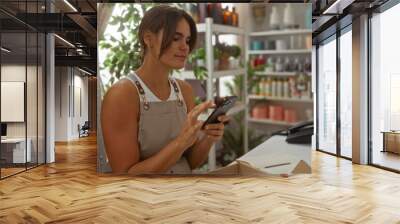 Woman using smartphone in home decor store surrounded by various decorative items and greenery Wall mural