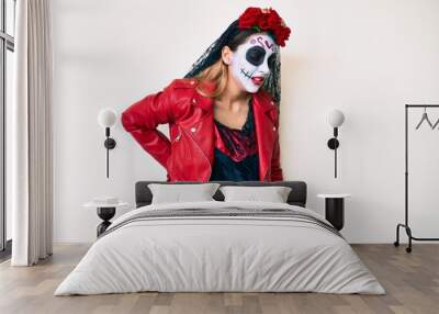 Woman wearing day of the dead costume over white suffering of backache, touching back with hand, muscular pain Wall mural