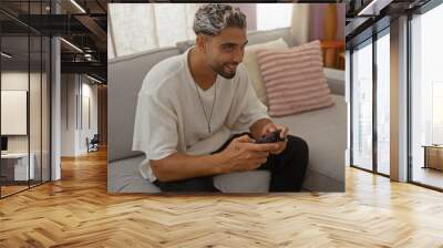 Young adult arabian man playing video games in a cozy living room with a relaxed atmosphere Wall mural