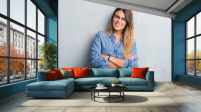 Young adult woman over grunge grey wall wearing glasses happy face smiling with crossed arms looking at the camera. Positive person. Wall mural