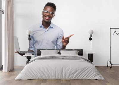 Young african american businessman using computer laptop very happy pointing with hand and finger to the side Wall mural