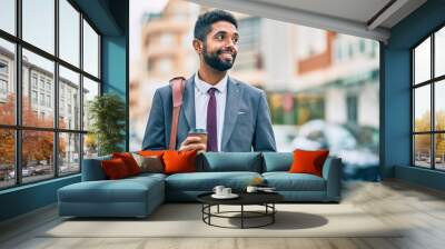 Young african american businessman using smartphone and drinking take away coffee at the city. Wall mural