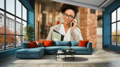 Young african american businesswoman smiling happy talking on the smartphone at the city. Wall mural